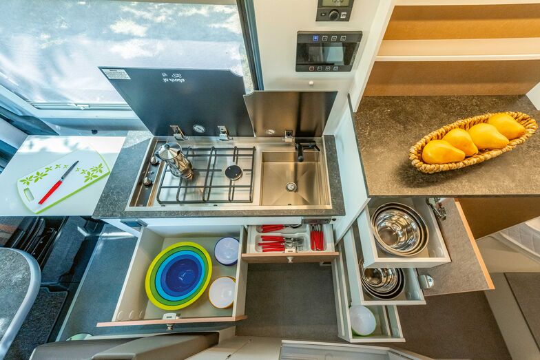 Küchenblock mit Auszügen, Arbeitsfläche, Spüle und zweiflammigem Kocher.